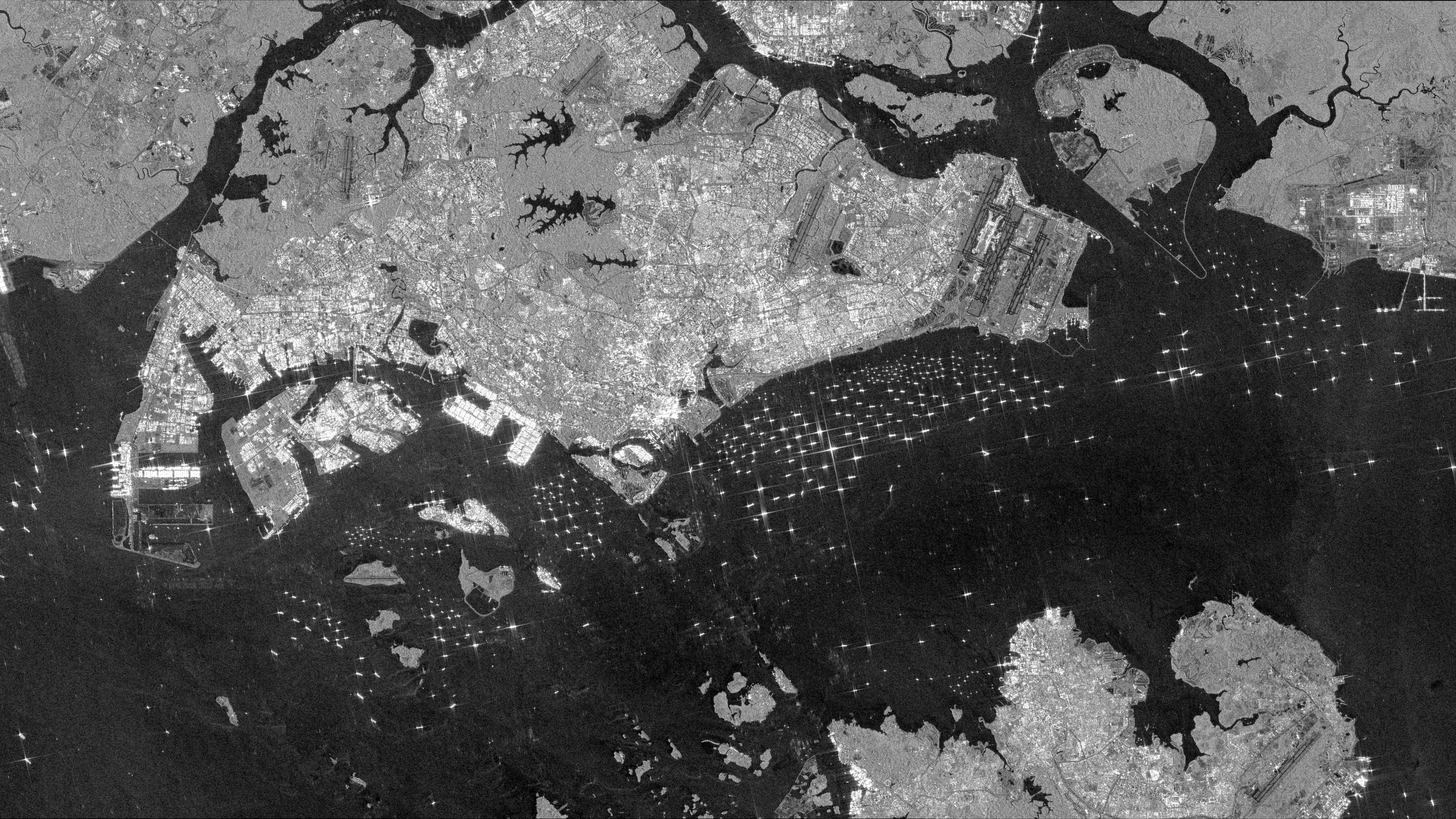 Black and white radar satellite image of the Singapore Strait showing many bright ships and fine wake lines on dark water.