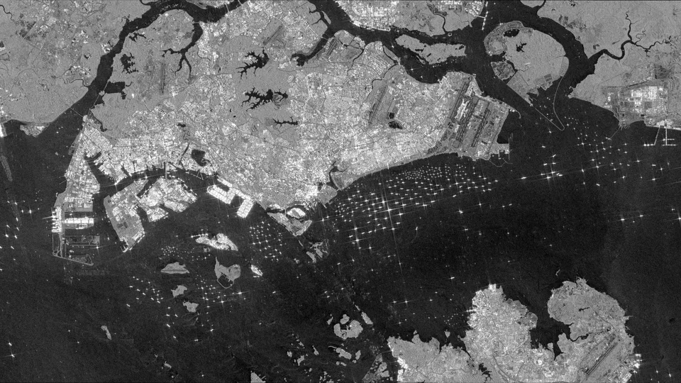 Black and white radar satellite image of the Singapore Strait showing many bright ships and fine wake lines on dark water.